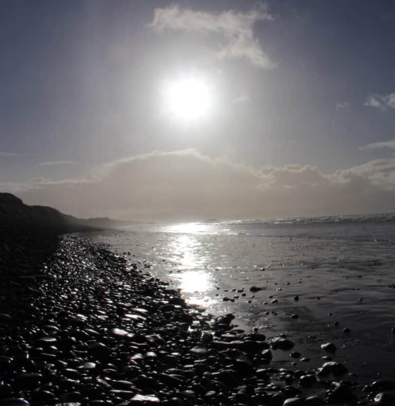 'Path' of sunlight on sea and pebble beach